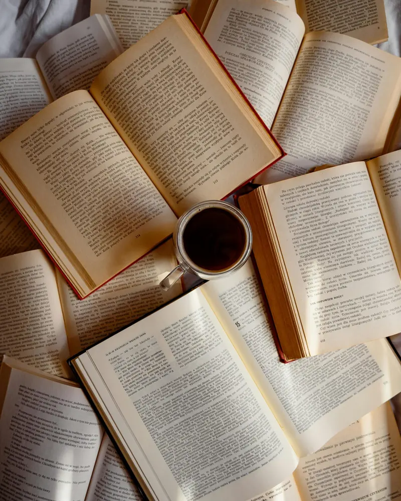 Aufgeschlagene Bücher und eine Tasse Kaffee auf dem Boden